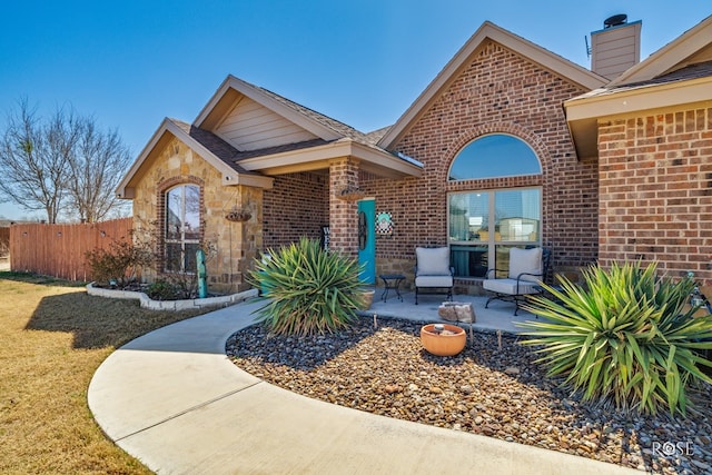 exterior space featuring stone siding, fence, a yard, brick siding, and a patio area