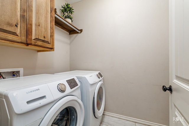 laundry area with baseboards, cabinet space, and washing machine and dryer