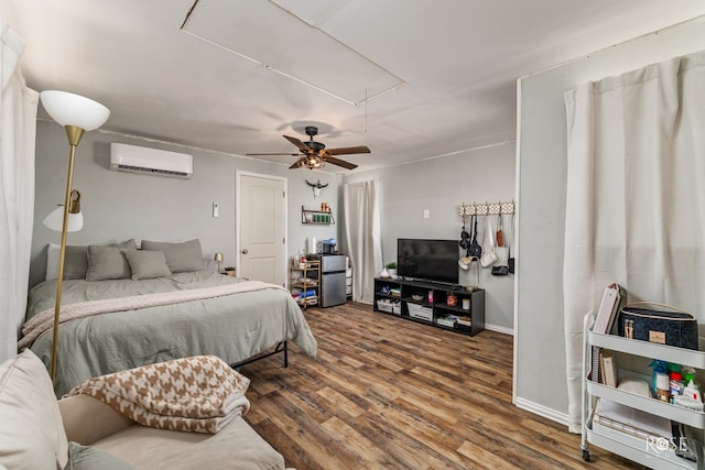 bedroom featuring wood finished floors, baseboards, attic access, ceiling fan, and an AC wall unit