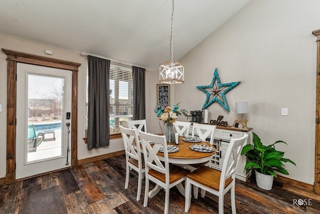 dining area featuring dark wood-style floors, a chandelier, baseboards, and lofted ceiling