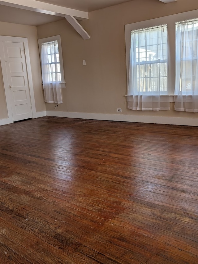 spare room with baseboards and dark wood-style flooring