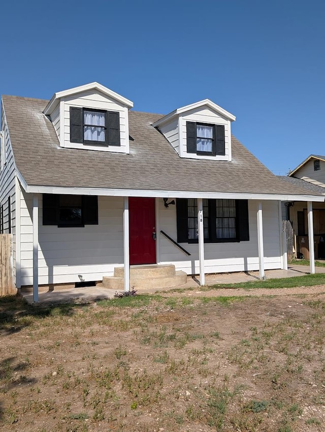 view of front facade featuring covered porch, fence, and a shingled roof