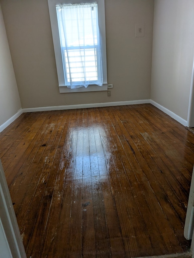 empty room featuring baseboards and hardwood / wood-style flooring