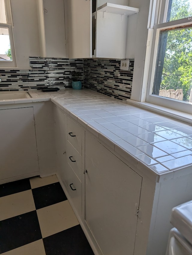 kitchen with white cabinetry, tile patterned floors, and decorative backsplash