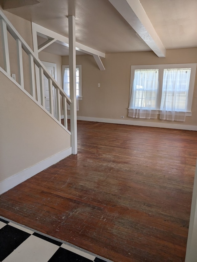unfurnished living room with stairs, baseboards, beam ceiling, and wood finished floors