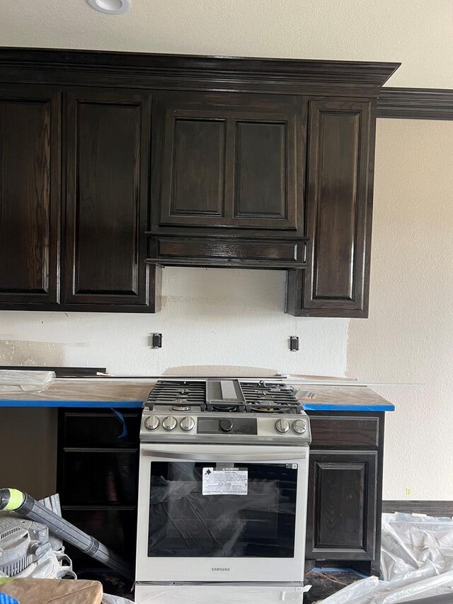 kitchen featuring crown molding, dark brown cabinets, exhaust hood, and stainless steel gas stove