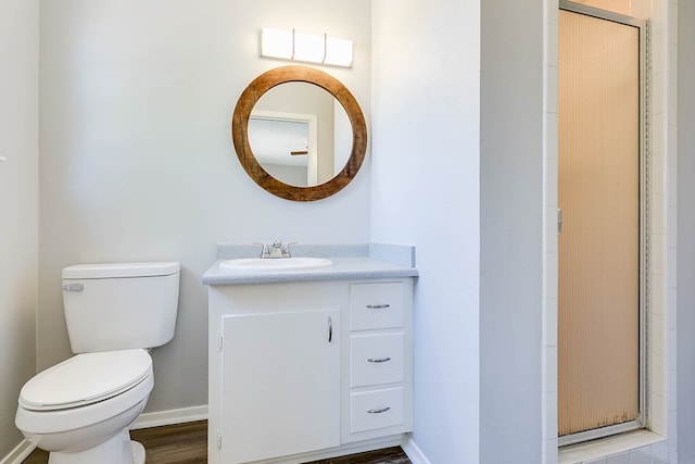 full bathroom with baseboards, a shower with door, vanity, and toilet