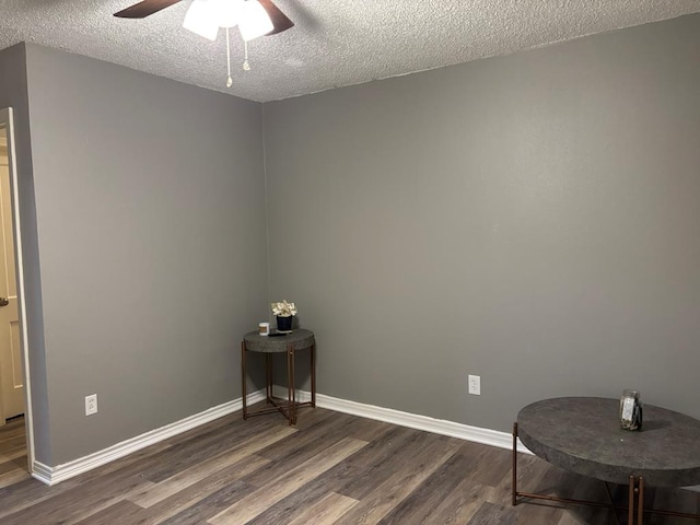 empty room with a textured ceiling, ceiling fan, dark wood-style flooring, and baseboards