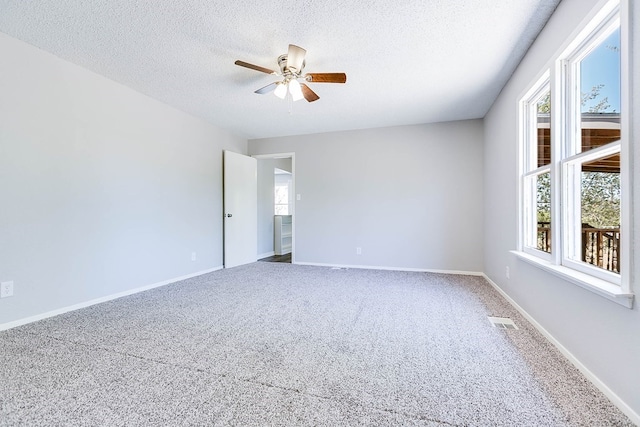 unfurnished room with a textured ceiling, carpet floors, visible vents, and baseboards