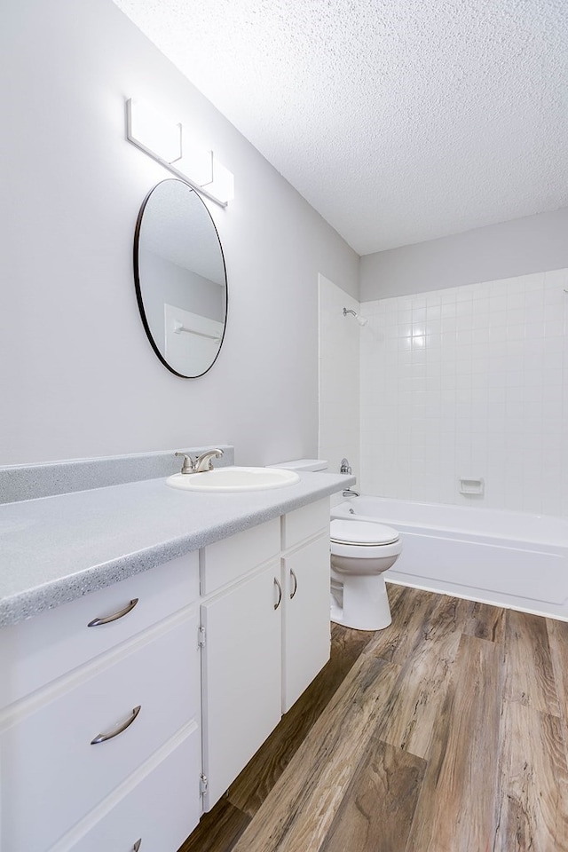 bathroom with shower / bathing tub combination, toilet, vanity, a textured ceiling, and wood finished floors