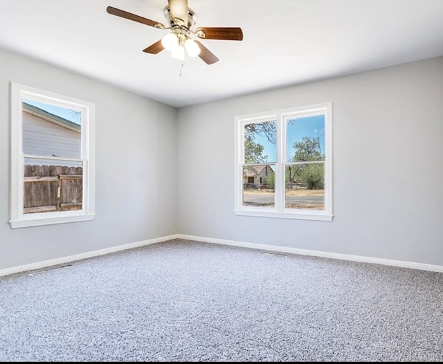 unfurnished room with carpet floors, baseboards, and a ceiling fan