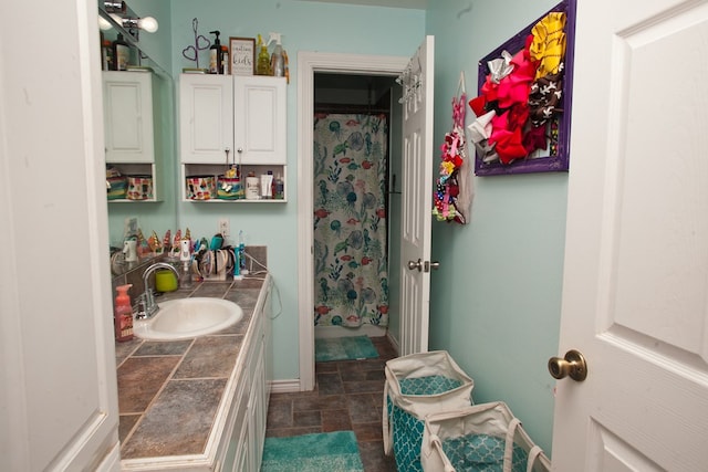 10581 Ballard Rd, San Angelo, TX 76901 - bathroom featuring stone finish floors, vanity, a shower with shower curtain, and baseboards