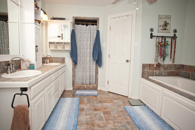 10581 Ballard Rd, San Angelo, TX 76901 - bathroom with a ceiling fan, a bath, baseboards, double vanity, and stone finish flooring