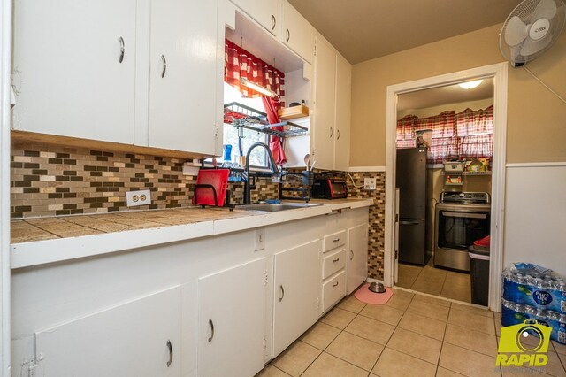 113 N Belaire Ave, San Angelo, TX 76905 - kitchen with stove, light tile patterned floors, a sink, and white cabinets