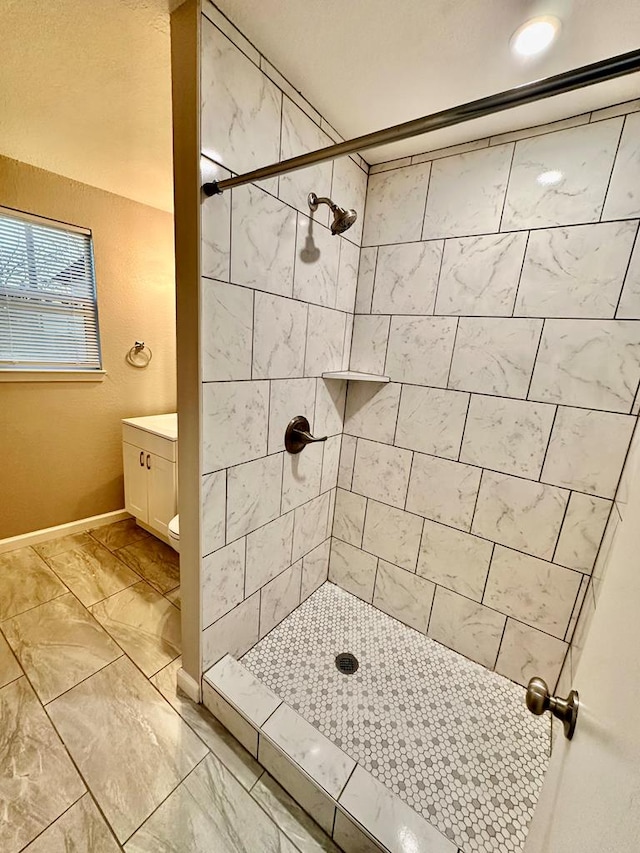 bathroom featuring tiled shower and vanity