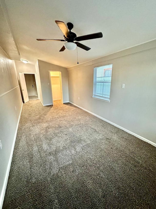 unfurnished bedroom with vaulted ceiling, carpet, a spacious closet, ceiling fan, and a closet