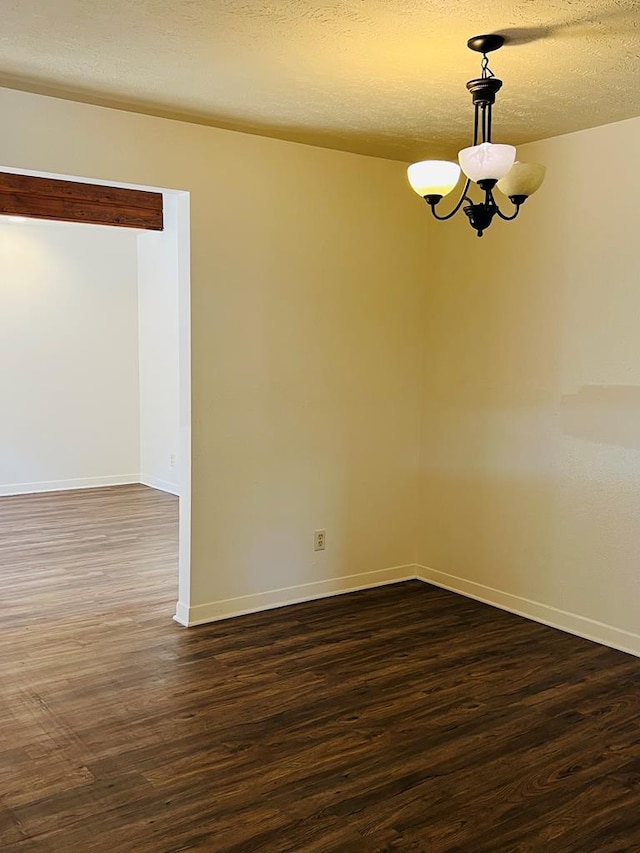 1723 Utah Ave, San Angelo, TX 76904 - spare room featuring a chandelier, dark wood-style floors, baseboards, and a textured ceiling