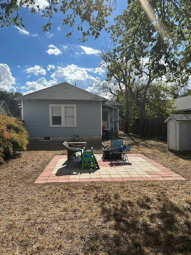 back of property with a storage shed and a patio area