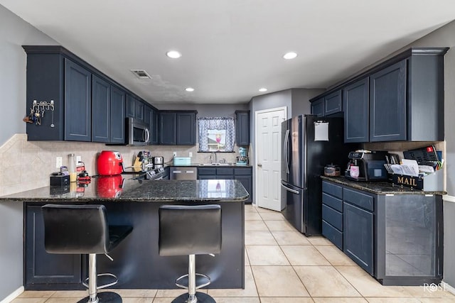 kitchen featuring light tile patterned floors, tasteful backsplash, visible vents, stainless steel microwave, and a peninsula