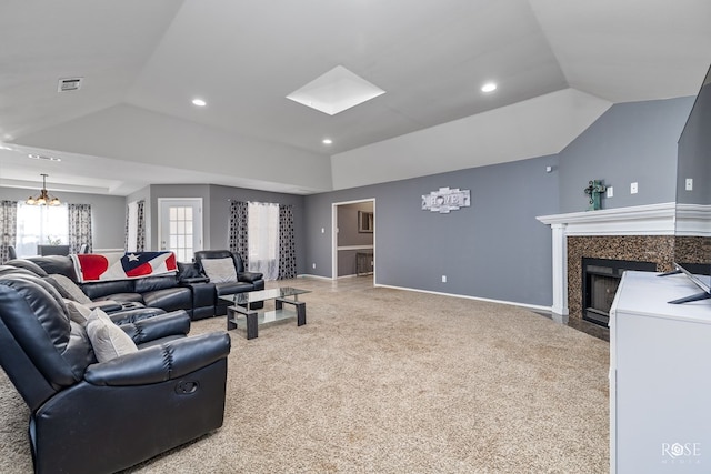 living room with a premium fireplace, an inviting chandelier, vaulted ceiling with skylight, light colored carpet, and a raised ceiling