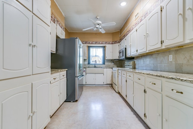 kitchen featuring tasteful backsplash, appliances with stainless steel finishes, white cabinetry, ceiling fan, and a sink