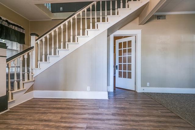 stairs with crown molding, visible vents, and wood finished floors