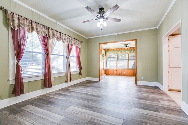 empty room featuring a wealth of natural light, crown molding, and wood finished floors