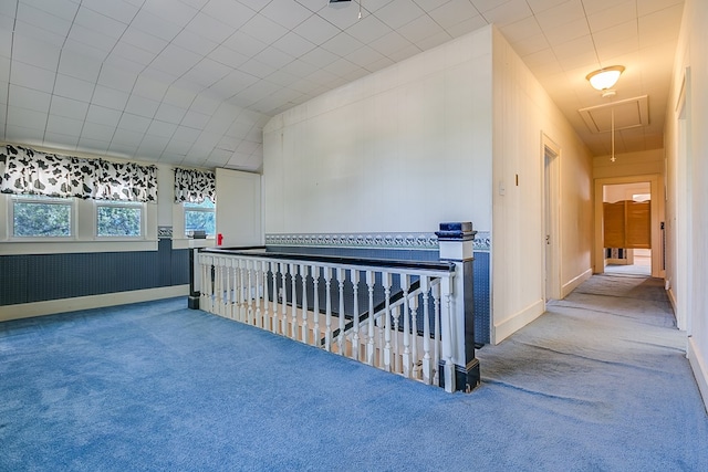 corridor with attic access, carpet, and baseboards