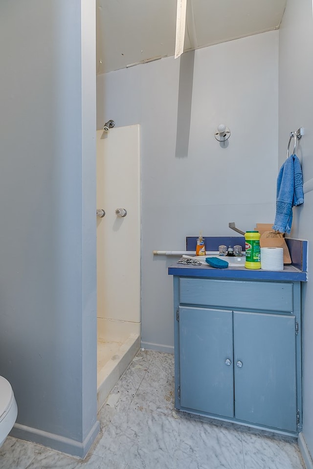 bathroom with a stall shower, toilet, vanity, and baseboards