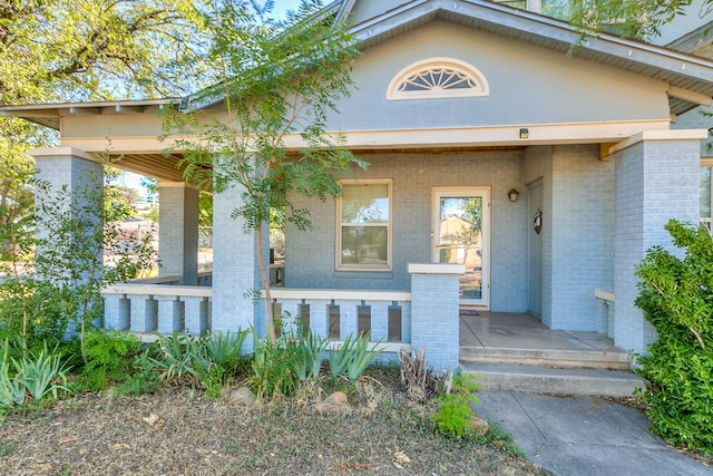 entrance to property with a porch and brick siding