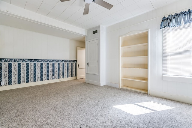 unfurnished room with ceiling fan, a wealth of natural light, carpet flooring, and visible vents