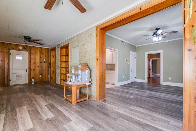 unfurnished living room featuring baseboards, visible vents, ceiling fan, wood finished floors, and crown molding