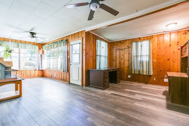 interior space with ceiling fan, wooden walls, and wood finished floors