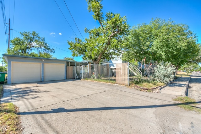 view of front facade featuring concrete driveway, an attached garage, and fence