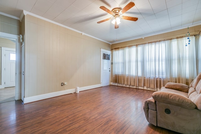 living area with ceiling fan, baseboards, crown molding, and wood finished floors