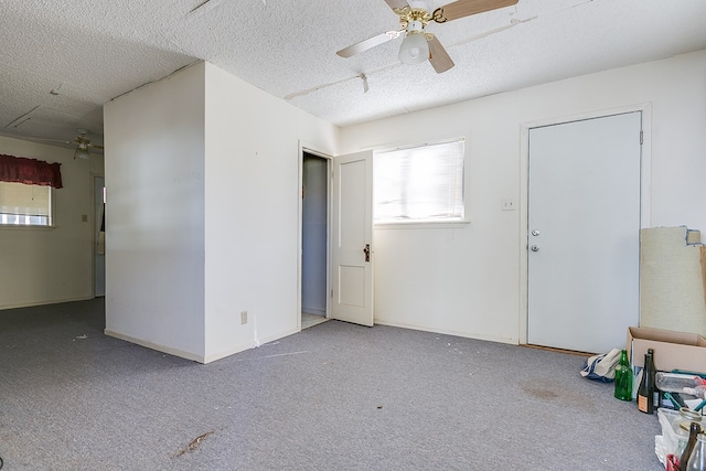 carpeted spare room with a textured ceiling, a ceiling fan, and baseboards