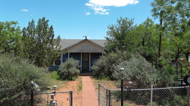  - view of property hidden behind natural elements featuring a gate and a fenced front yard
