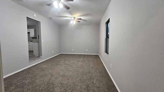 empty room featuring ceiling fan and dark carpet