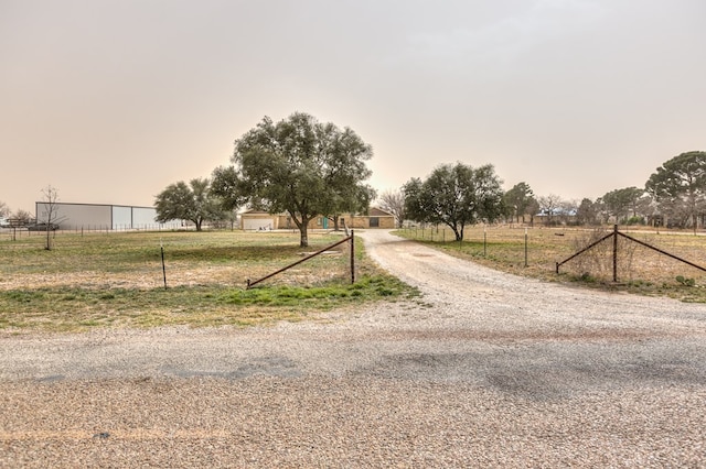 view of road with a rural view and gravel driveway