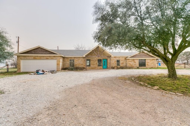 ranch-style house with a garage, stone siding, driveway, and fence