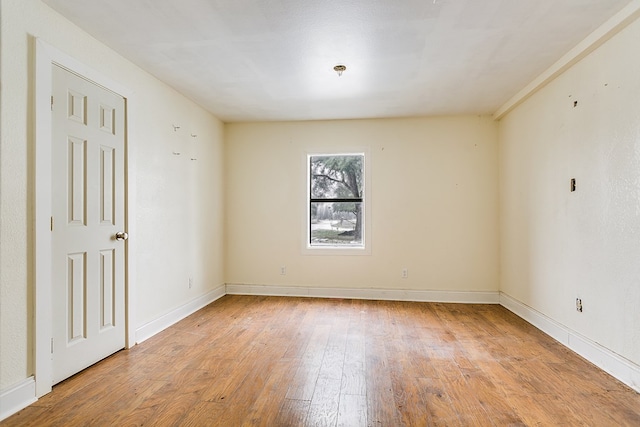 spare room with baseboards and light wood finished floors