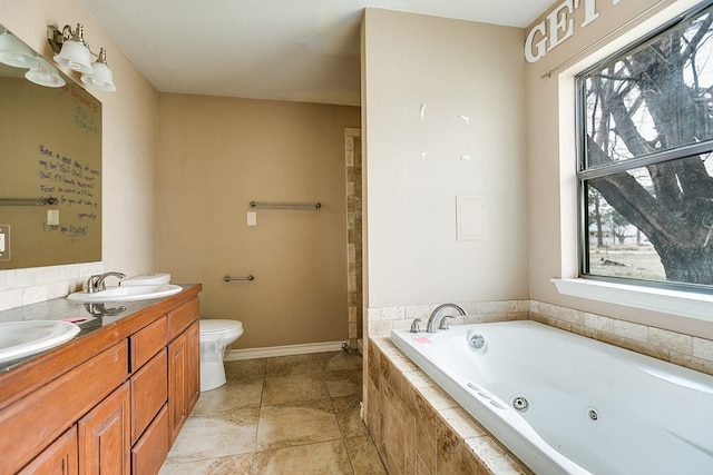 bathroom with a tub with jets, baseboards, double vanity, a sink, and toilet