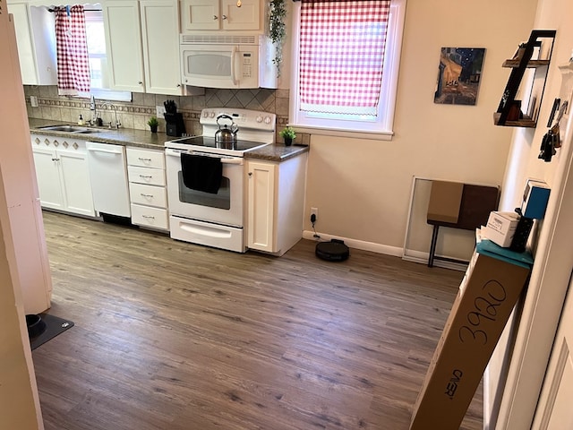 kitchen with sink, white appliances, dark hardwood / wood-style floors, white cabinets, and decorative backsplash