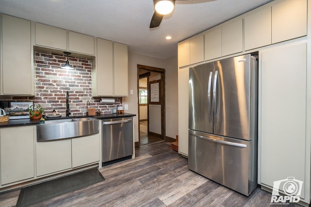 715 E Main St, Bronte, TX 76933 - kitchen with appliances with stainless steel finishes, a sink, dark countertops, cream cabinetry, and dark wood finished floors