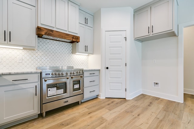 kitchen with light hardwood / wood-style flooring, double oven range, light stone counters, and custom exhaust hood