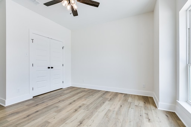 unfurnished bedroom with light wood-type flooring, ceiling fan, and a closet