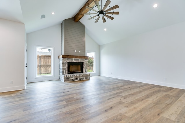 unfurnished living room with high vaulted ceiling, a large fireplace, ceiling fan, light hardwood / wood-style floors, and beam ceiling