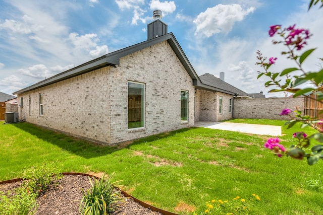 rear view of house with cooling unit, a patio, and a lawn