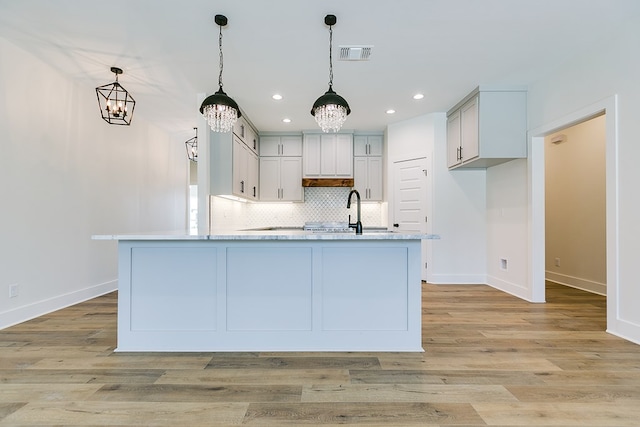 kitchen with sink, decorative light fixtures, and light hardwood / wood-style flooring