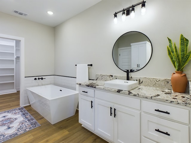 bathroom featuring vanity, a washtub, and wood-type flooring